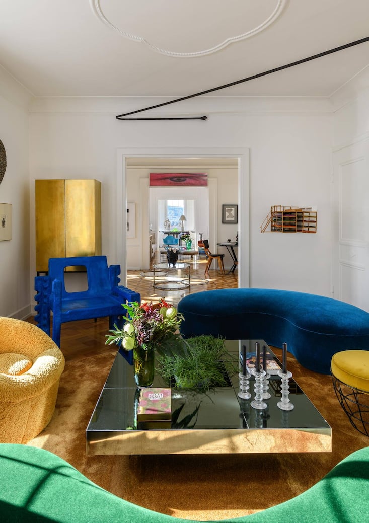 Die Samtsofas im Salon sind Kreationen des Pariser Designer-Trios Pierre Augustin Rose, der grün reflektierende Tisch wurde von Willy Rizzo entworfen. Den Messingschrank hat die Hausherrin als Bar gestaltet und vom Schreiner bauen lassen. Die Schlange an der Decke hat der Künstler Valentin Carron aus Martigny kreiert. Der blaue Stuhl ist ein Unikat des Designers Savvas Laz.