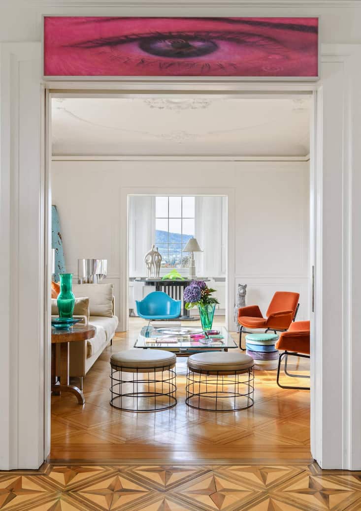 Das rote Auge über dem Durchgang ist ein Werk von Pamela Rosenkranz. In diesem Salon dominieren Vintage-Stücke und ein Hocker des dänischen Künstlers Cristian Andersen. Das witzige Möbel erinnert an ein Luxemburgerli.