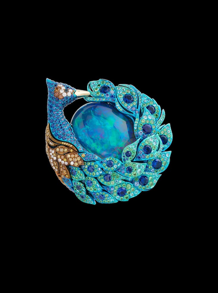 <p>Ein Pfau umschliesst mit seinem schillernden Schweif – vollständig mit Farbsteinen ausgefasst – einen prachtvollen Opal.</p>