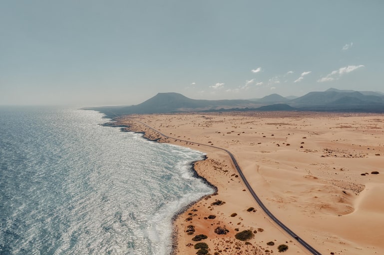 Rocky coastline and highway with golden sand and blue water