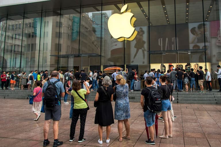 In this Friday, Sept. 21, 2018, photo, foreign tourists watch people queue in line to enter the Apple Store for the debut of the latest iPhones in Shanghai. China imposed new tariff hikes on U.S. goods on Monday, Sept. 24, 2018, and accused Washington of bullying, giving no sign of compromise in an intensifying battle over technology that is weighing on global economic growth. (Chinatopix via AP) (KEYSTONE/AP CHINATOPIX/)